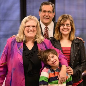 A family of four poses while smiling.