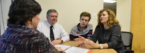 A family of three at a table in an office discusses special needs trusts with trust director.